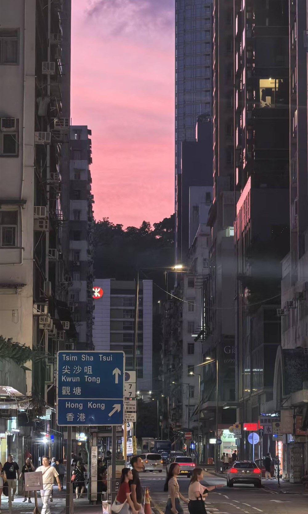 粉色晚霞下的香港街道、楼宇、路牌与过街行人